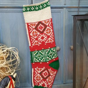 Hand-knitted Fair Trade Christmas stocking in red, green, and cream with traditional pattern.