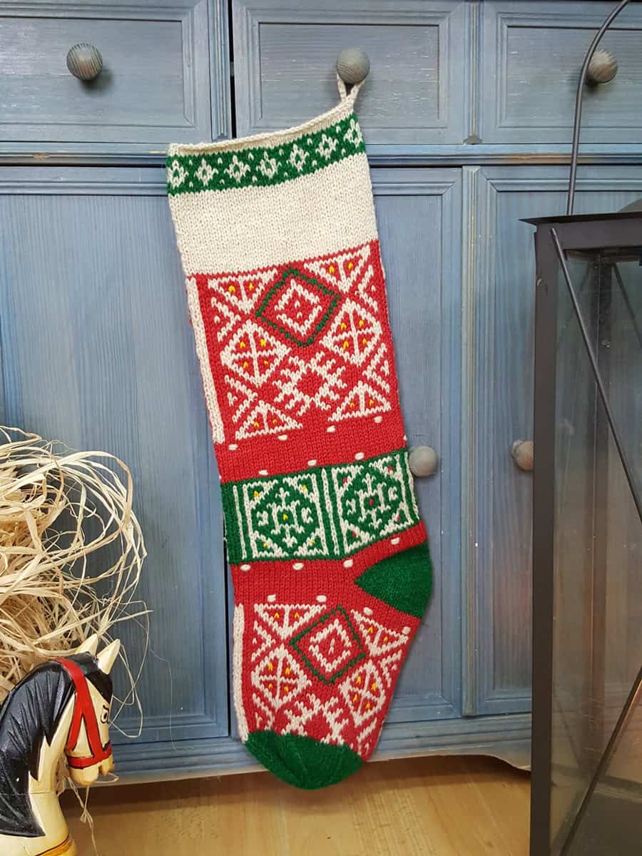 Hand-knitted Fair Trade Christmas stocking in red, green, and cream with traditional pattern.