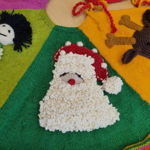 Close-up of Santa appliqué on green wedge of Hand Knit Christmas Tree Skirt