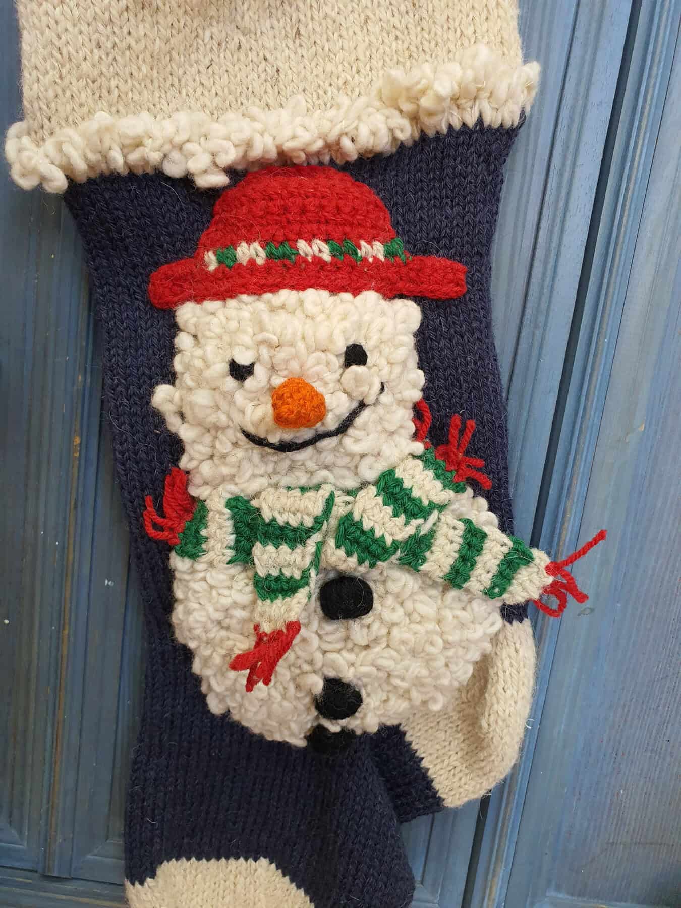 Close-up of snowman appliqué on hand-knit personalized Christmas stocking