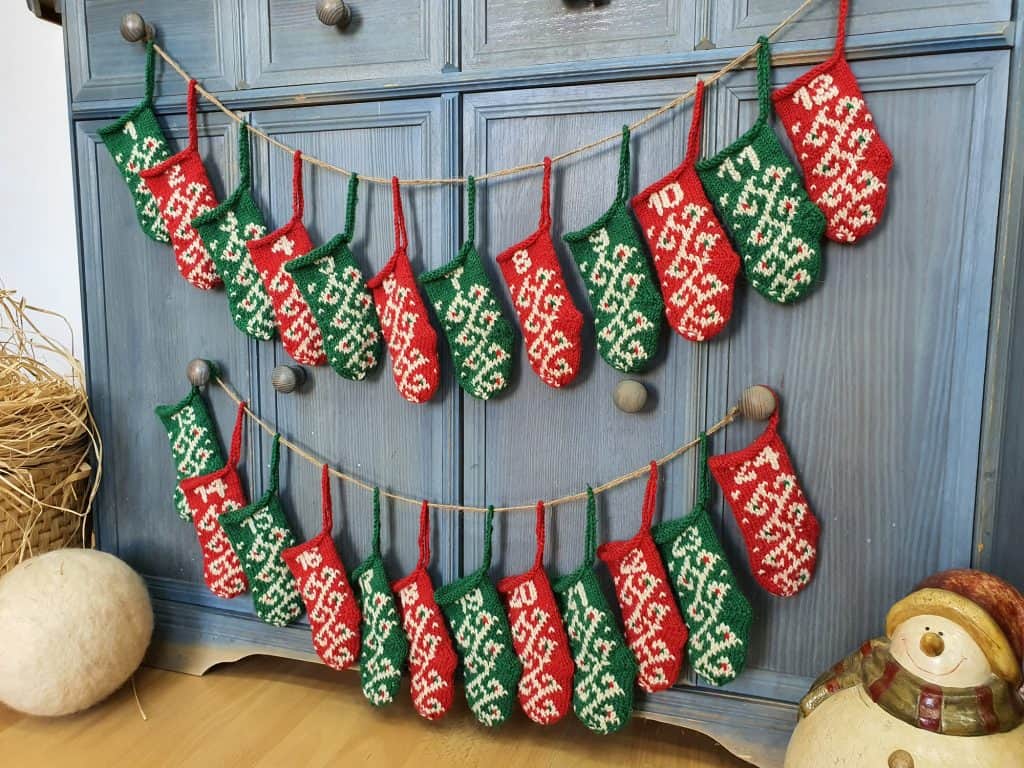Hand-knit Christmas advent calendar garland of 24 mini stockings hanging on a wall