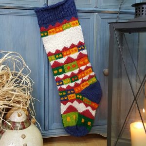 Village holiday scene on Christmas stocking displayed hanging