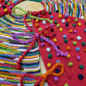 Close-up of hand-crocheted Christmas tree skirt with colorful stitches in red, green, mustard, and white.