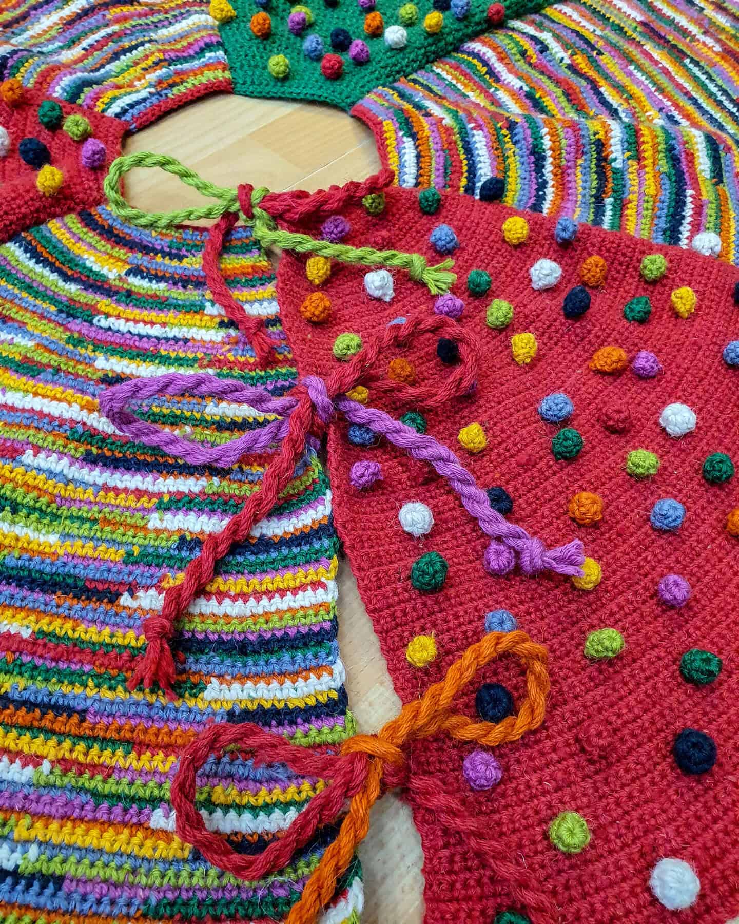 Close-up of hand-crocheted Christmas tree skirt with colorful stitches in red, green, mustard, and white.