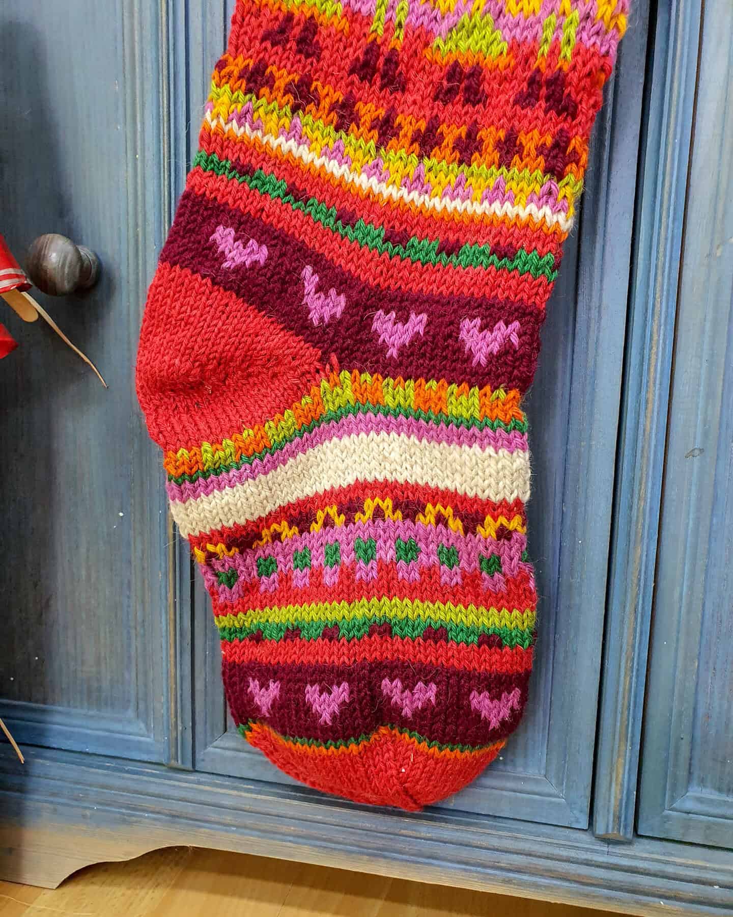 Close-up of heart motif on personalized striped Christmas stocking.