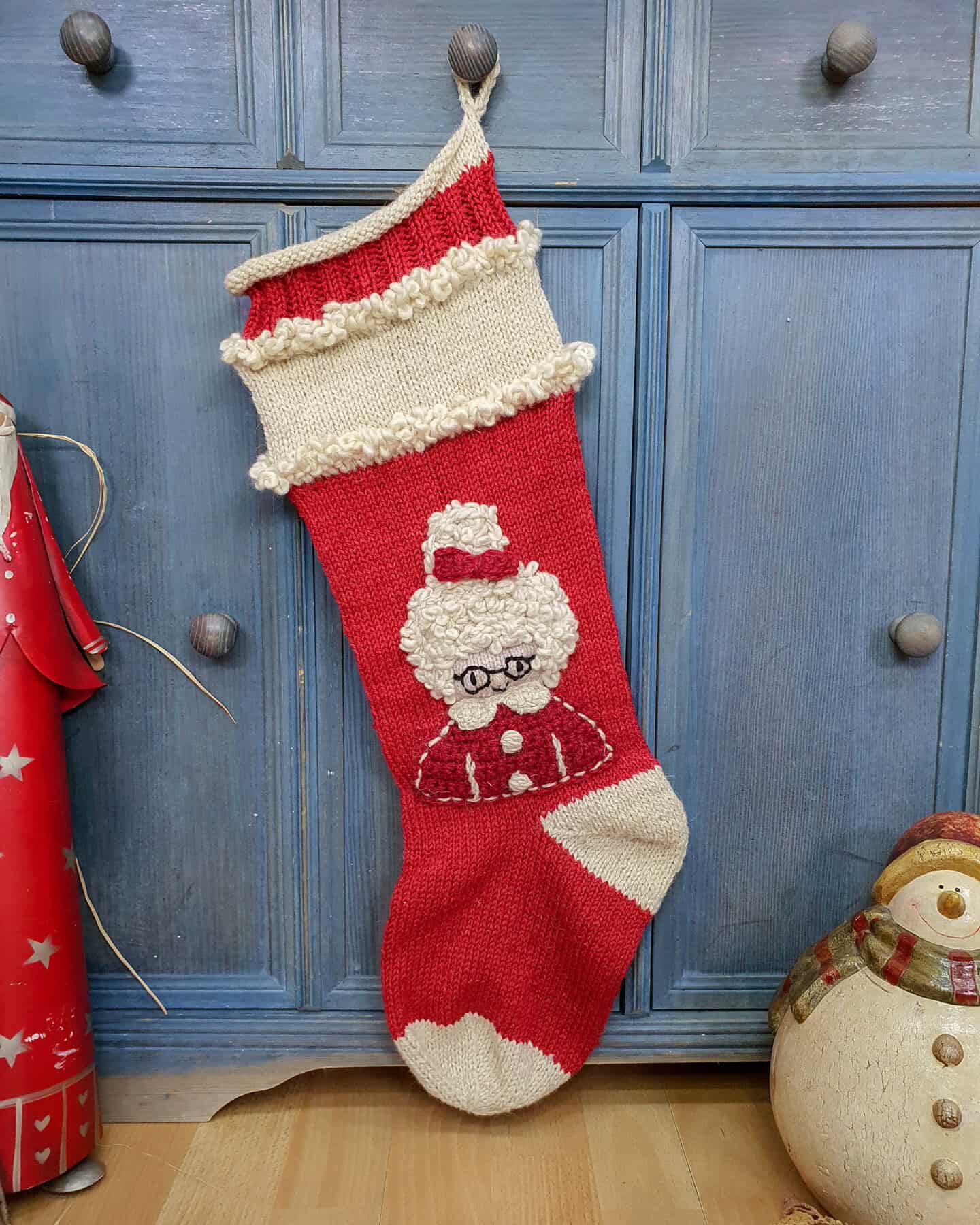 Hand-knitted red and cream Christmas stocking with Mrs. Claus design.