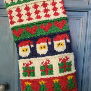 Close-up of top part of hand-knitted Christmas stocking with festive patterns.