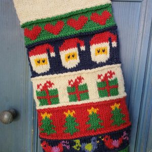 Close-up of the top part of a personalized Christmas stocking, hand-knitted with festive motifs.