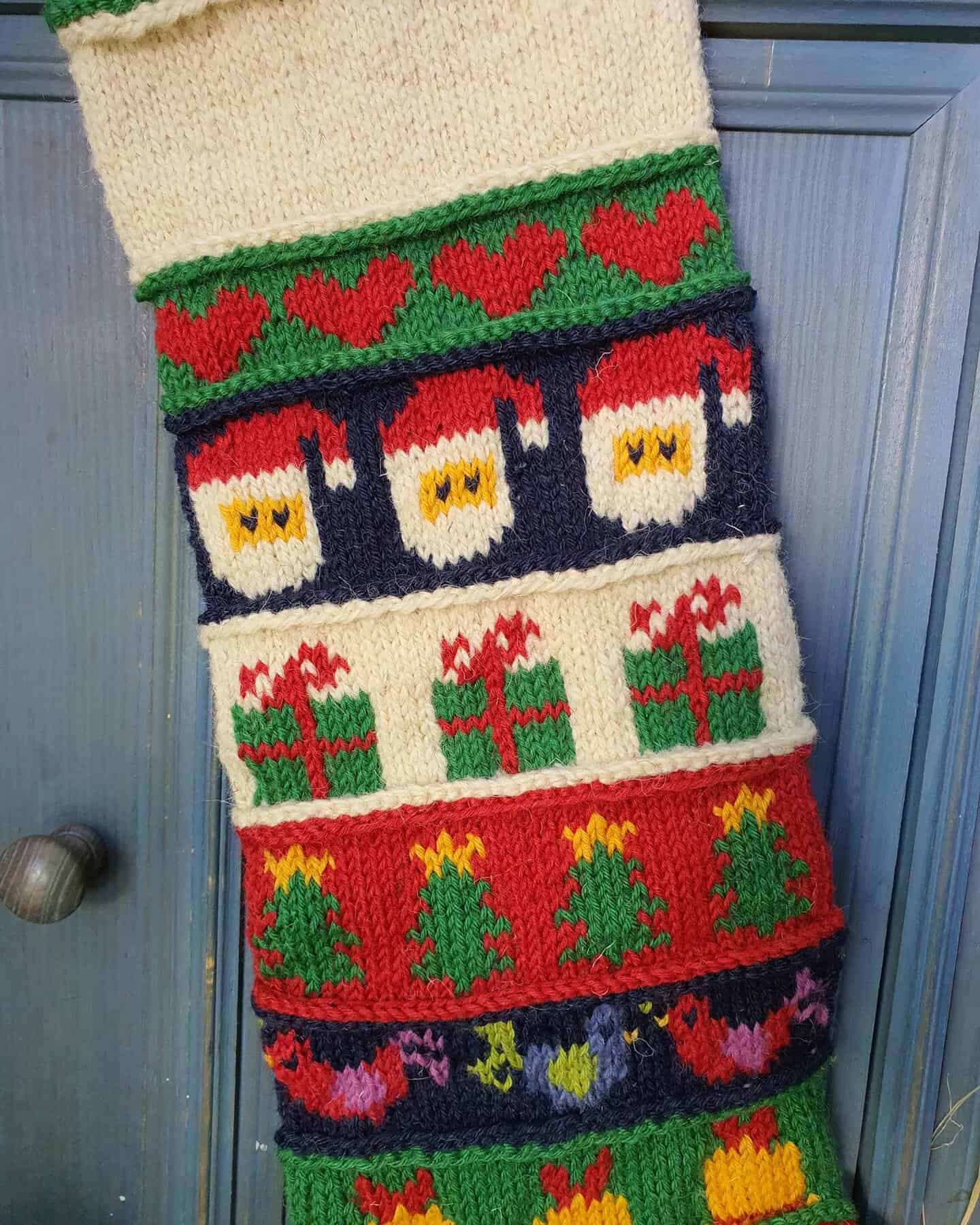 Close-up of the top part of a personalized Christmas stocking, hand-knitted with festive motifs.
