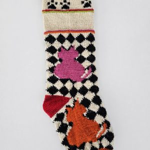 Hand-knitted checker-pattern Christmas stocking with pink and orange cat motifs.