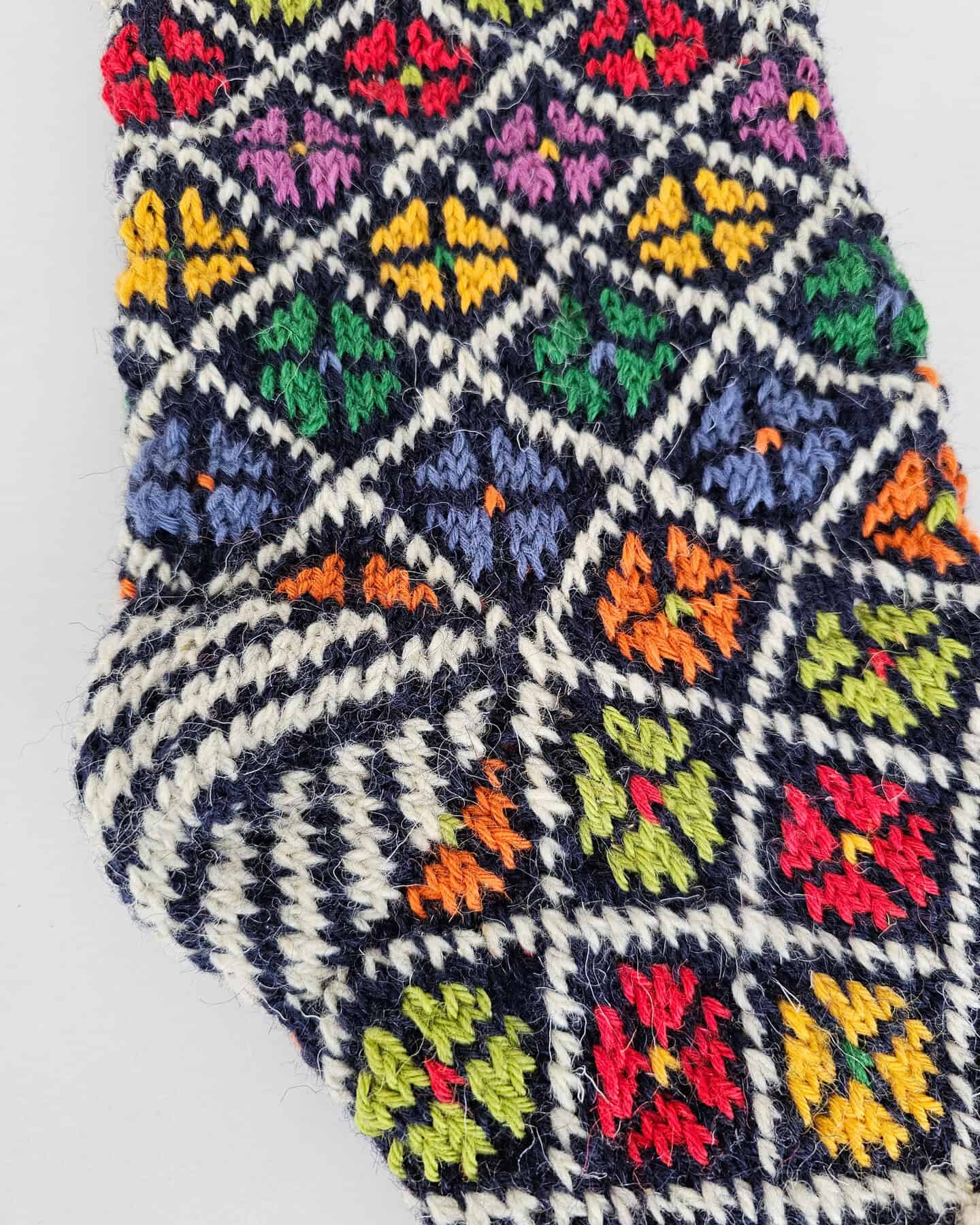 Detailed view of a colorful knitted Christmas stocking with floral patterns, can be personalized with a Custom Name