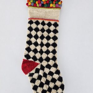 Bold dogtooth patterned stocking in cream and black, adorned with red and green bobbles at heel, toe, and cuff.