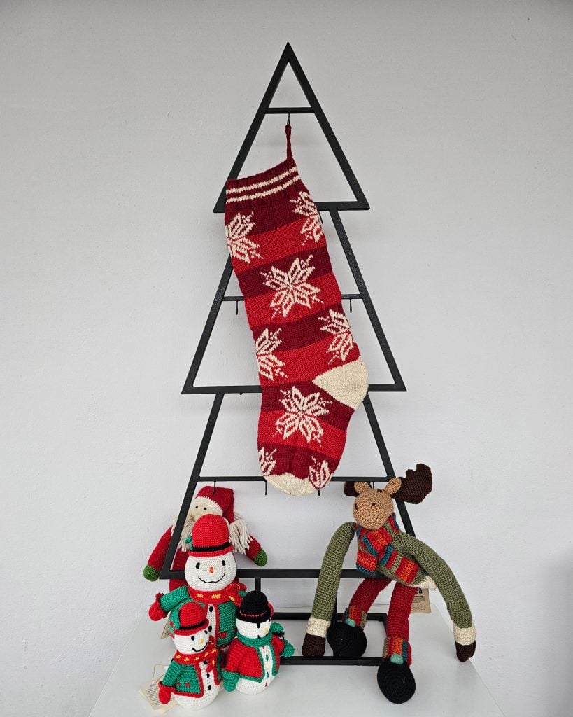 Red hand-knitted fair trade snowflake Christmas stocking hanging on Christmas tree shape