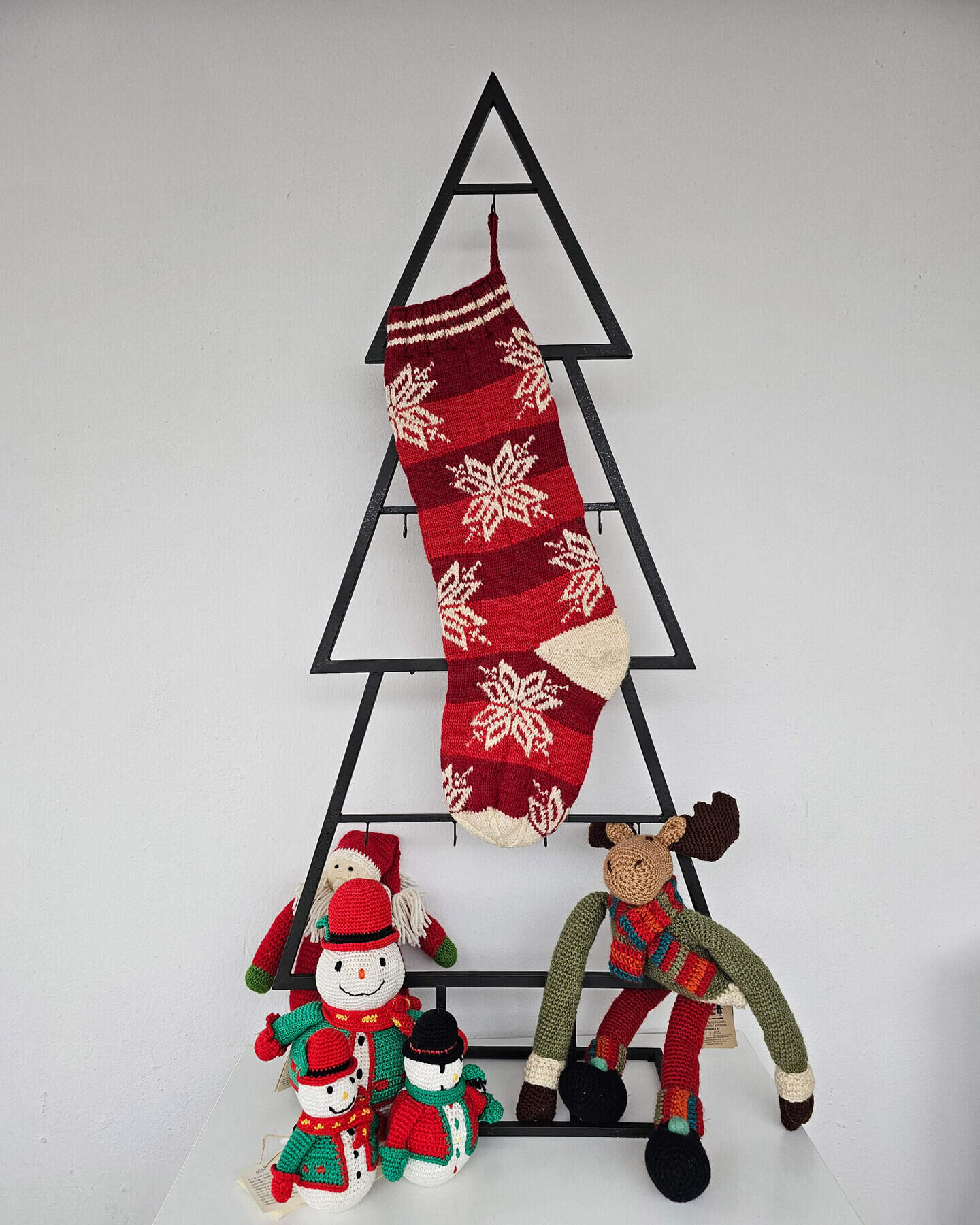 Red hand-knitted fair trade snowflake Christmas stocking hanging on Christmas tree shape