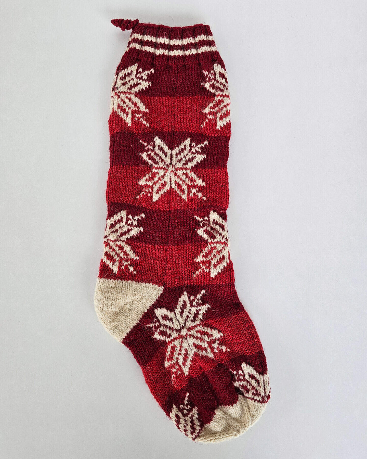 Hand-knitted red Christmas stocking with timeless snowflake pattern