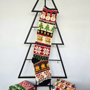 Handmade Christmas stocking with Christmas symbols displayed with holiday decorations and gifts.