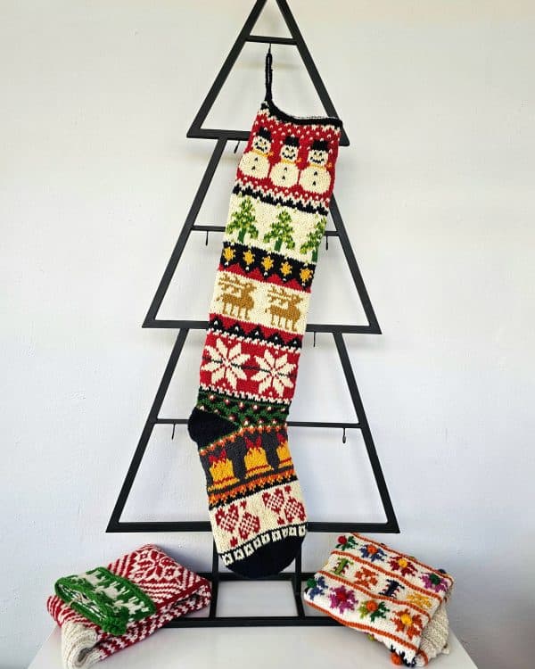 Handmade Christmas stocking with Christmas symbols displayed with holiday decorations and gifts.