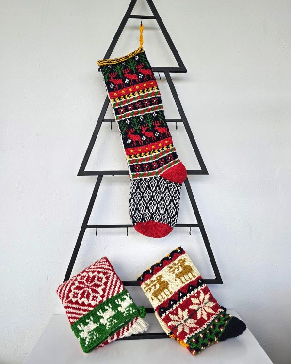 Handmade Christmas stocking with reindeer design displayed with holiday decorations.