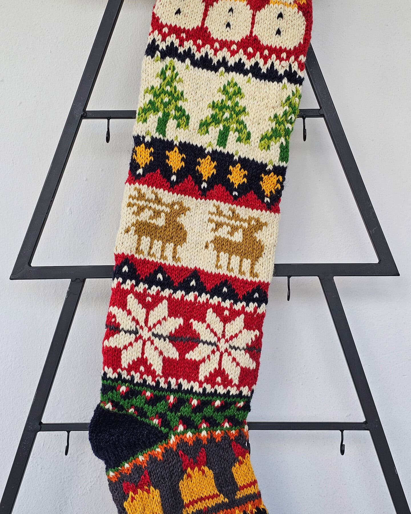 Handmade Christmas stocking held in hand showing detailed Christmas symbols including Santa, reindeer, snowflakes, and Christmas trees.