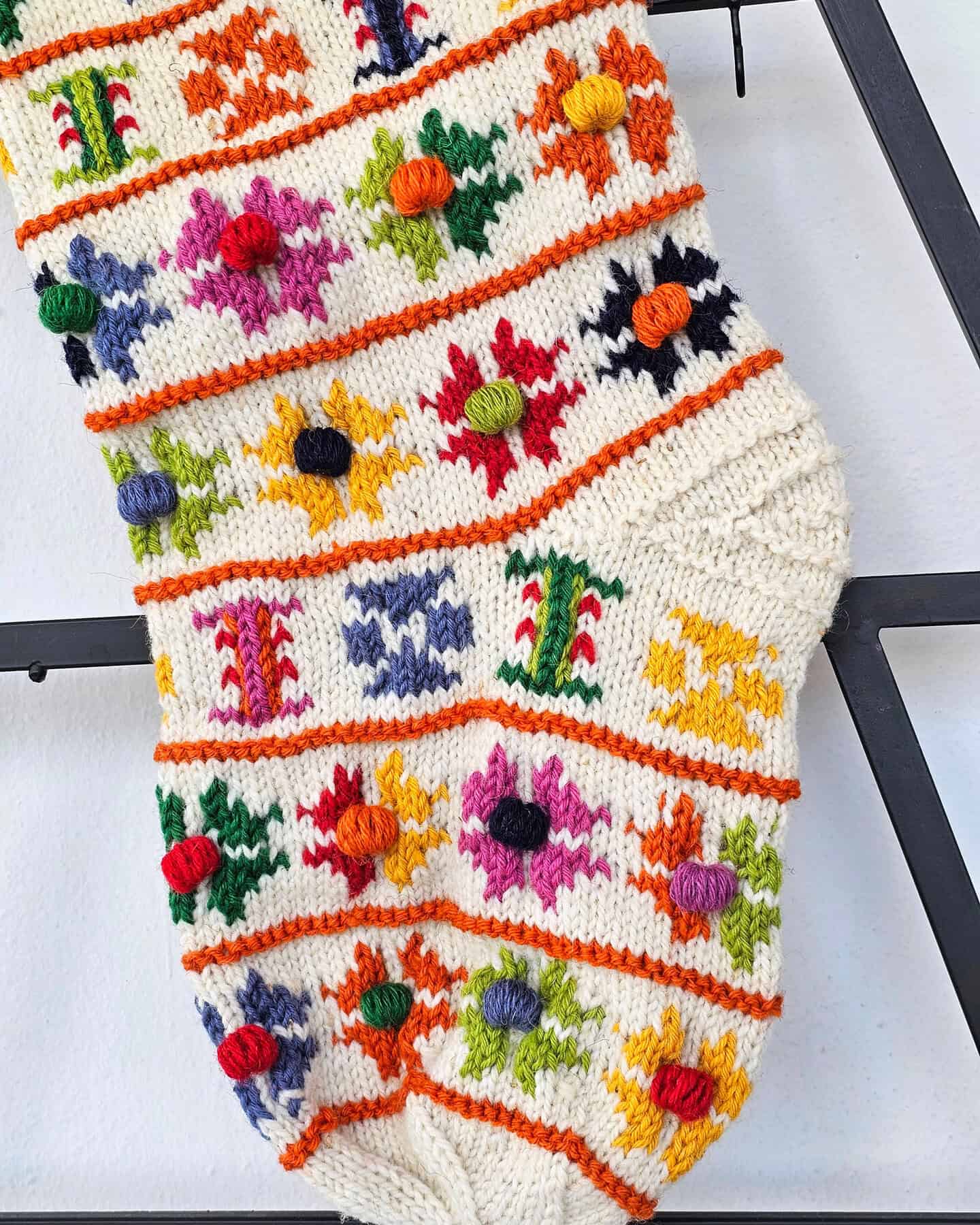 Detailed knit stitches and pom-pom accents on artisan holiday stocking