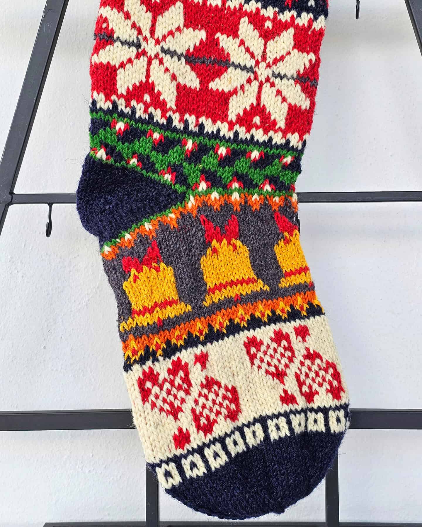 Close-up of the intricate knit patterns and Christmas symbols on the handmade stocking.