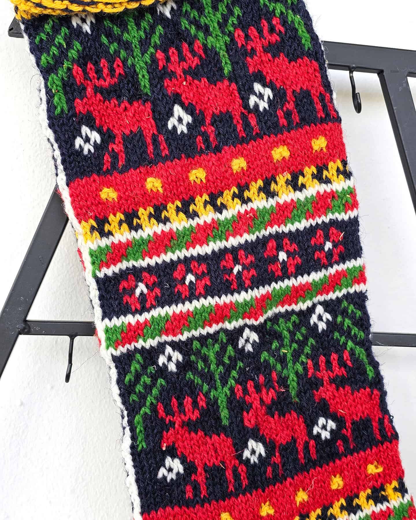 Close-up of handmade Christmas stocking heel showing red and white knit patterns complementing the reindeer design.