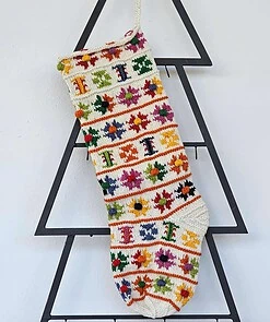 Hand-knit Christmas stocking with colorful floral patterns and pom-poms