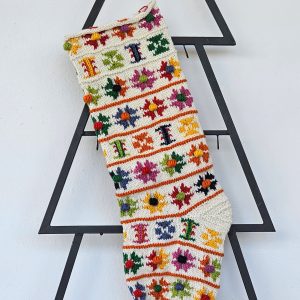 Hand-knit Christmas stocking with colorful floral patterns and pom-poms