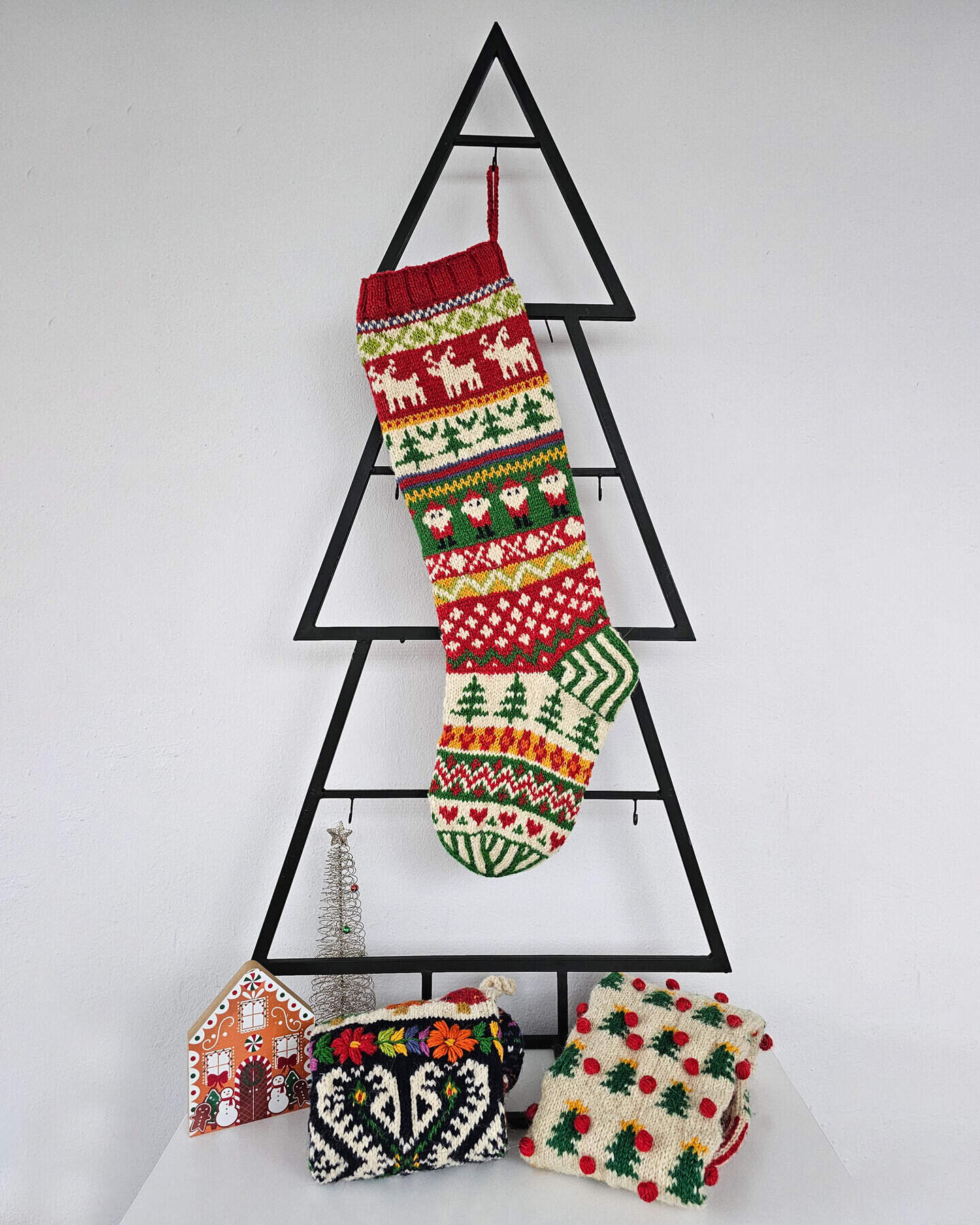Christmas stocking displayed on a Christmas tree shape with holiday decorations.