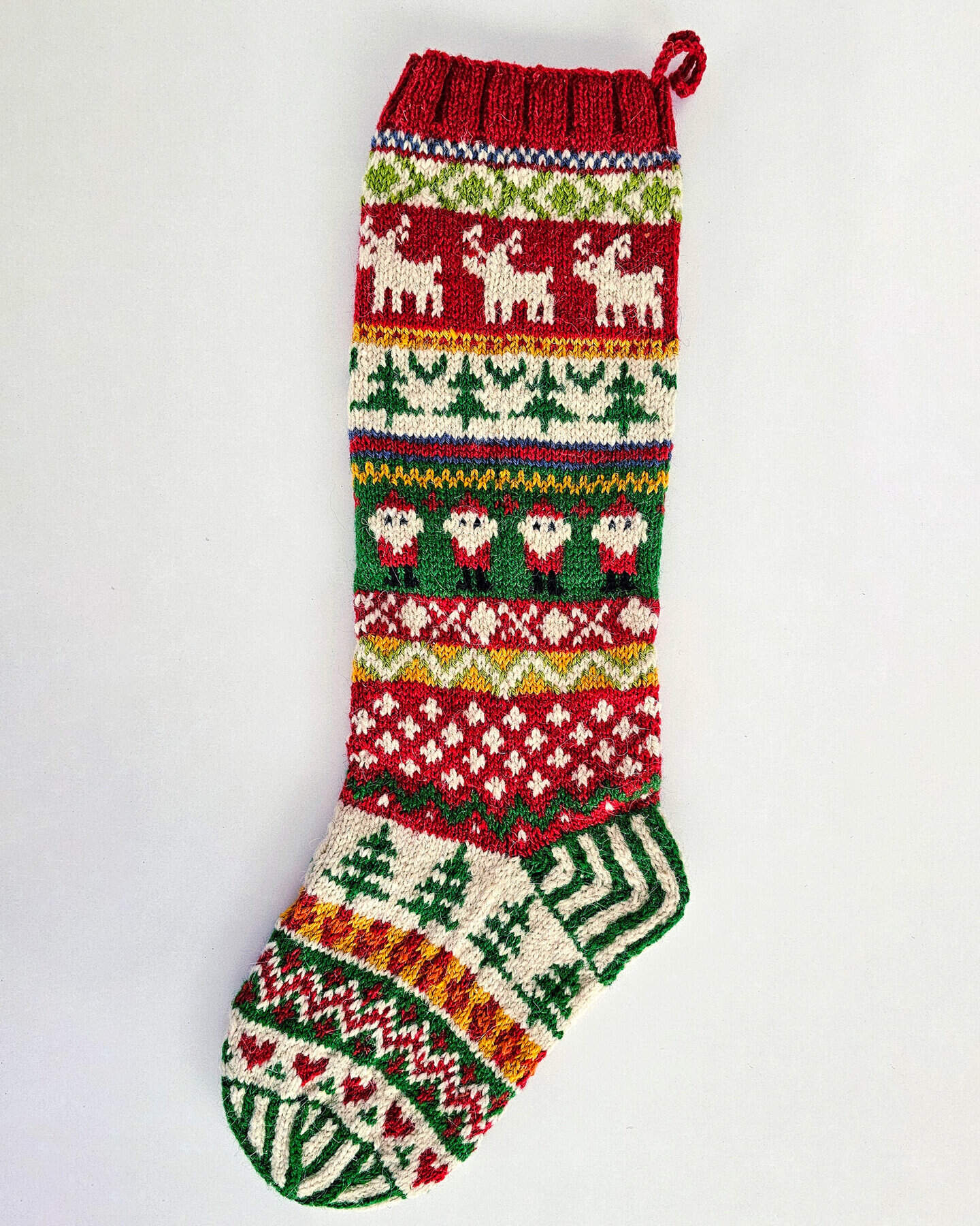 Handcrafted Christmas stocking featuring reindeer, Santa, and Nordic patterns in red, green, and cream.