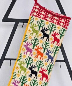 Close-up of a colorful knitted Christmas stocking with snowmen, trees, and bells in red, white, green, and blue yarn.