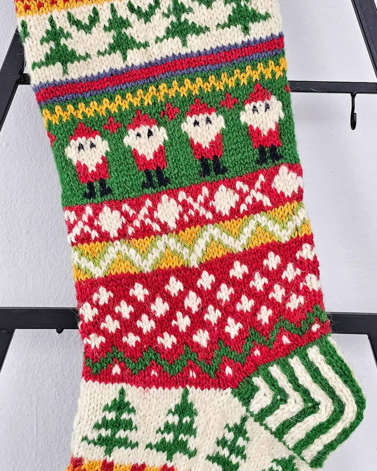 Close-up of intricate Nordic patterns on a Christmas stocking, highlighting reindeer and Santa designs.