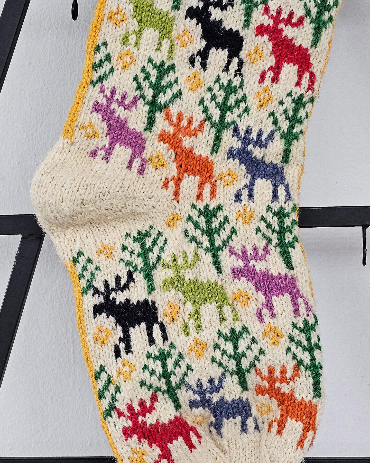 Handmade Christmas stocking with bright red, white, and green patterns, featuring snowmen and Christmas trees.