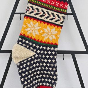 Close-up of hand-knit texture and snowflake pattern on Christmas stocking.