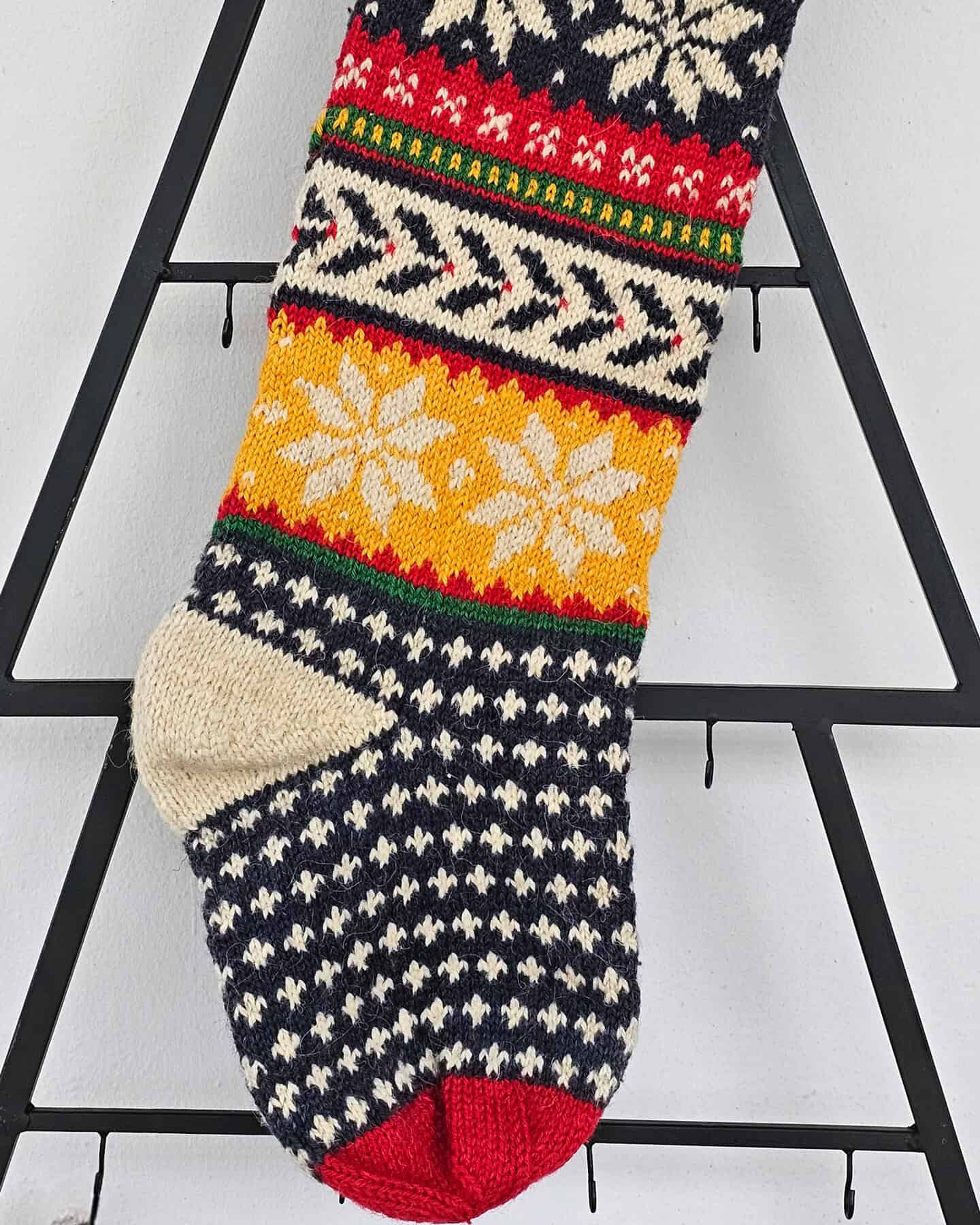 Close-up of hand-knit texture and snowflake pattern on Christmas stocking.