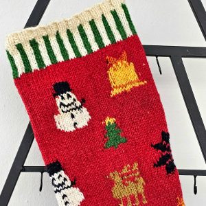 Handmade Christmas stocking with festive red, green, and white knit patterns and holiday motifs