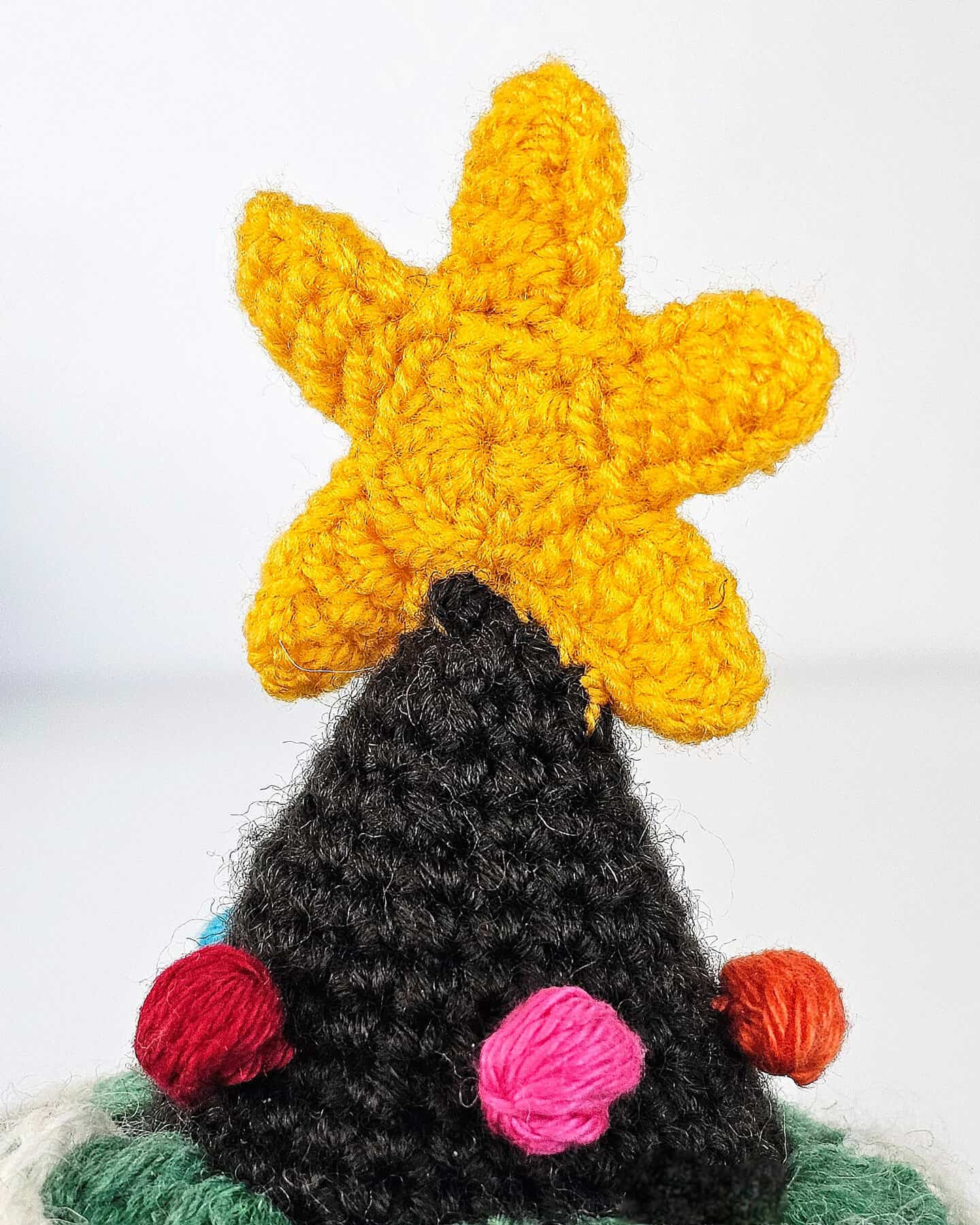 Top-down view of a crocheted fair trade Christmas tree ornament with a yellow star topper and multicolor bobble eco-friendly decorations.