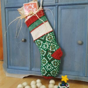Personalized holiday stocking handmade from natural fibers, featuring festive red and green patterns.