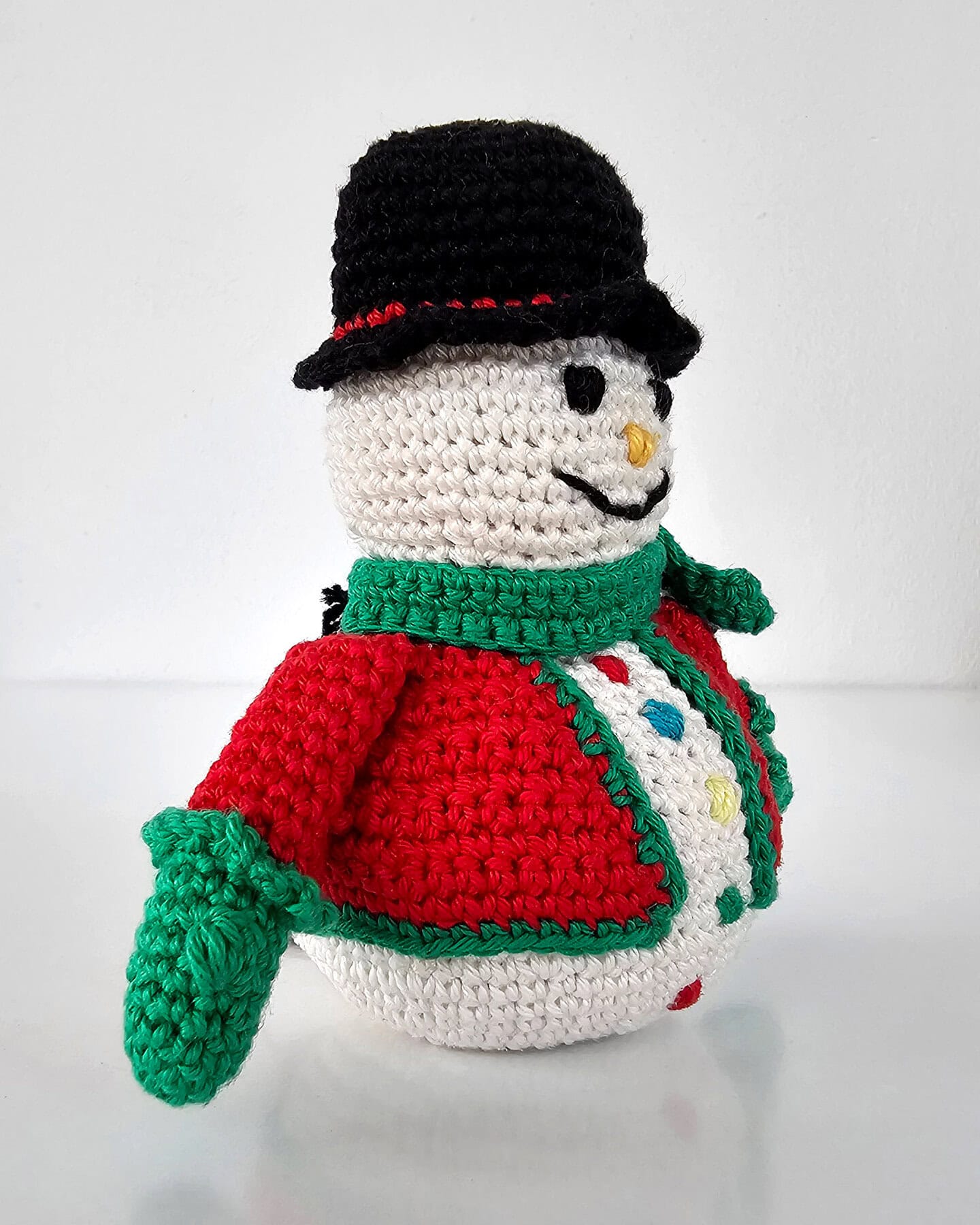 Handmade crochet snowman ornament with festive jacket and scarf