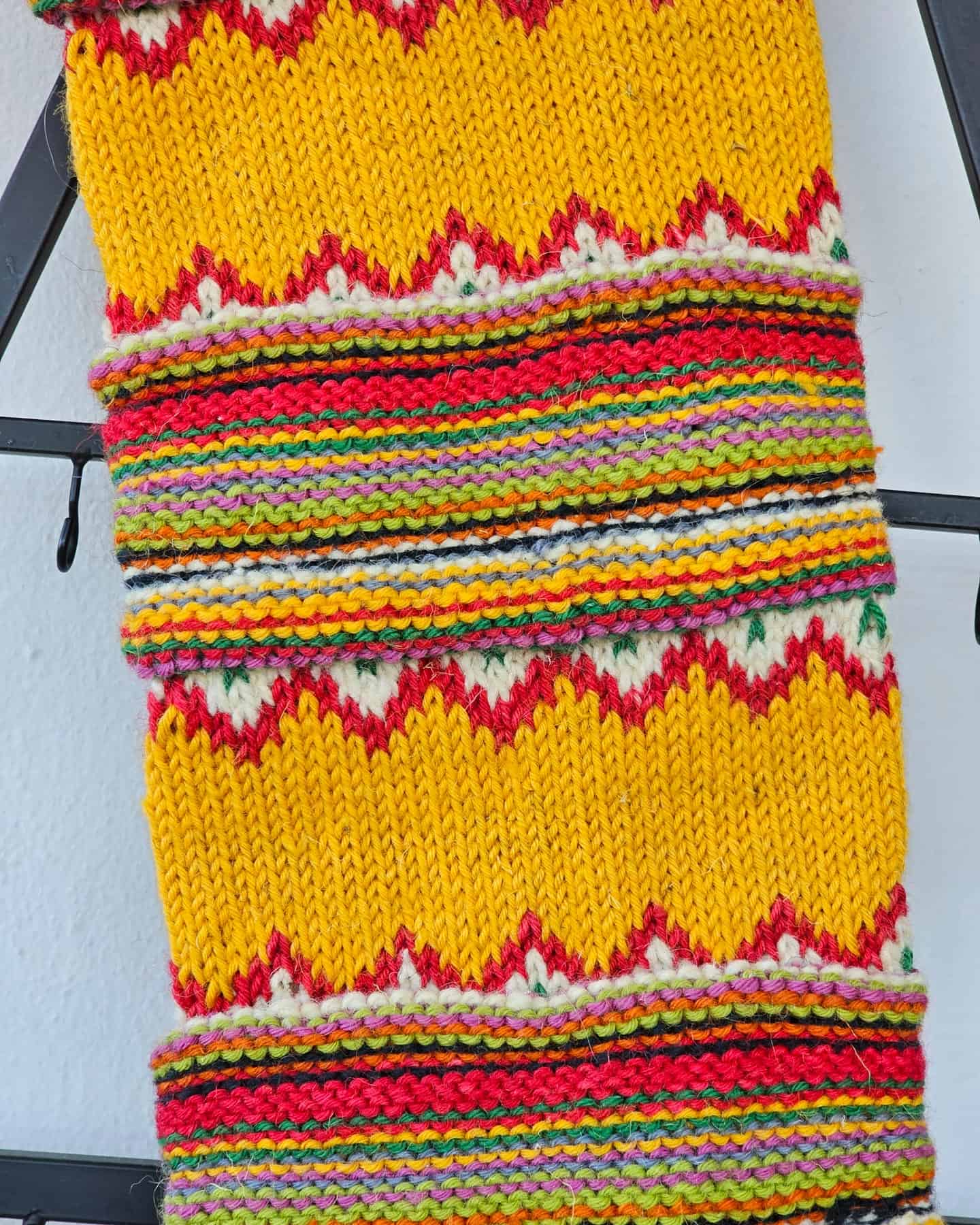 Close-up of hand-knitted fair-trade Christmas stocking with colorful stripes and yellow zigzag Fair Isle pattern.