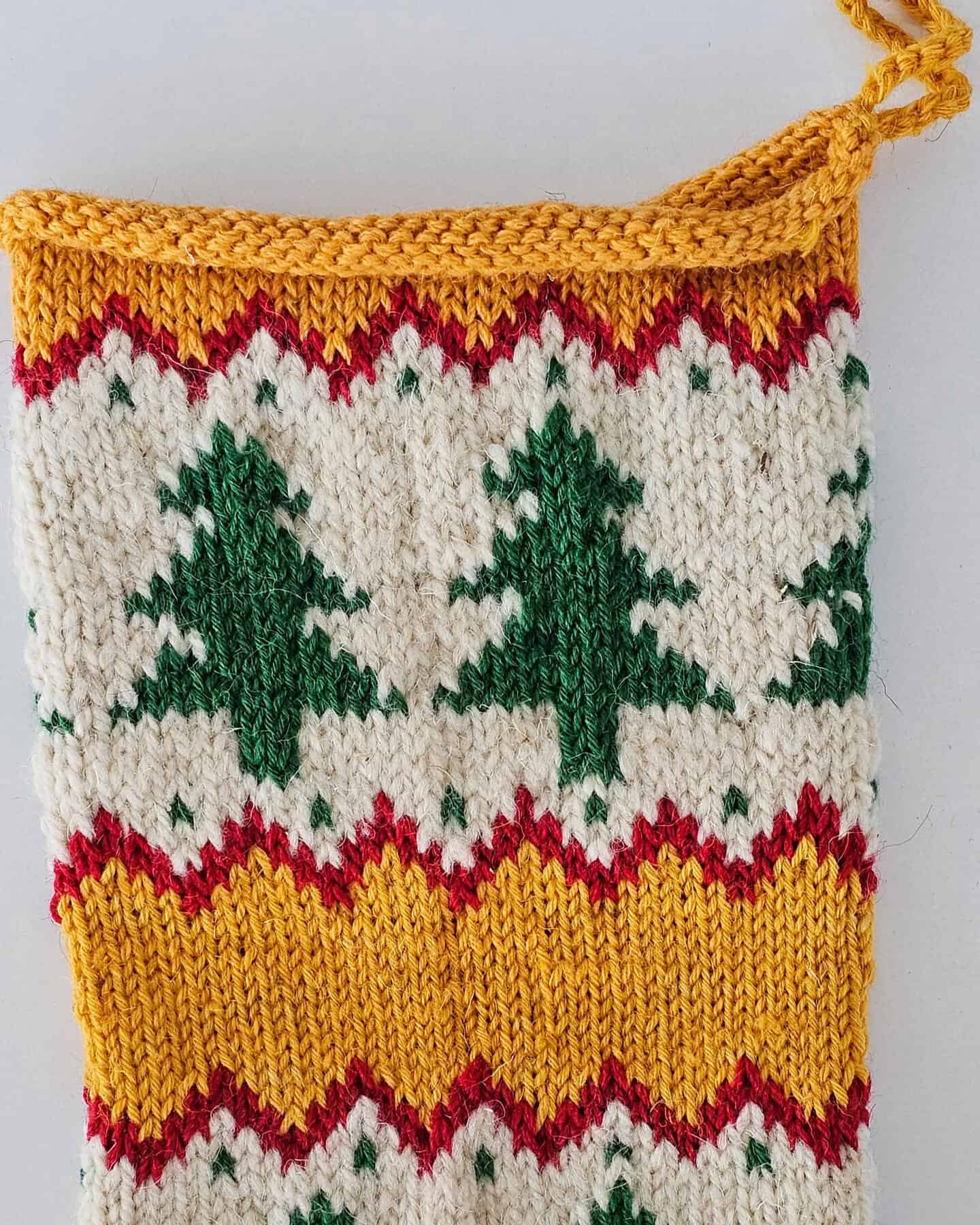 Hand‑knitted yellow and white Christmas stocking with festive tree design for your holiday home decor