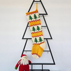 Hand‑knitted Christmas stocking with festive green tree design on red and cream background