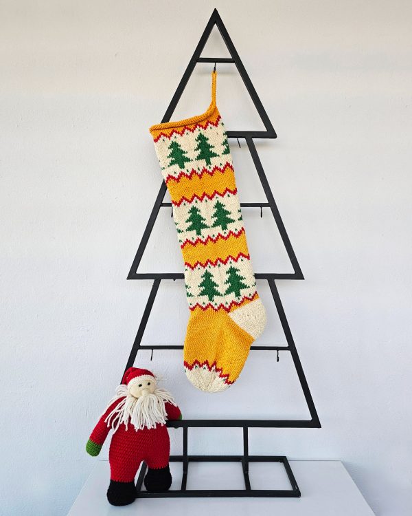 Hand‑knitted Christmas stocking with festive green tree design on red and cream background