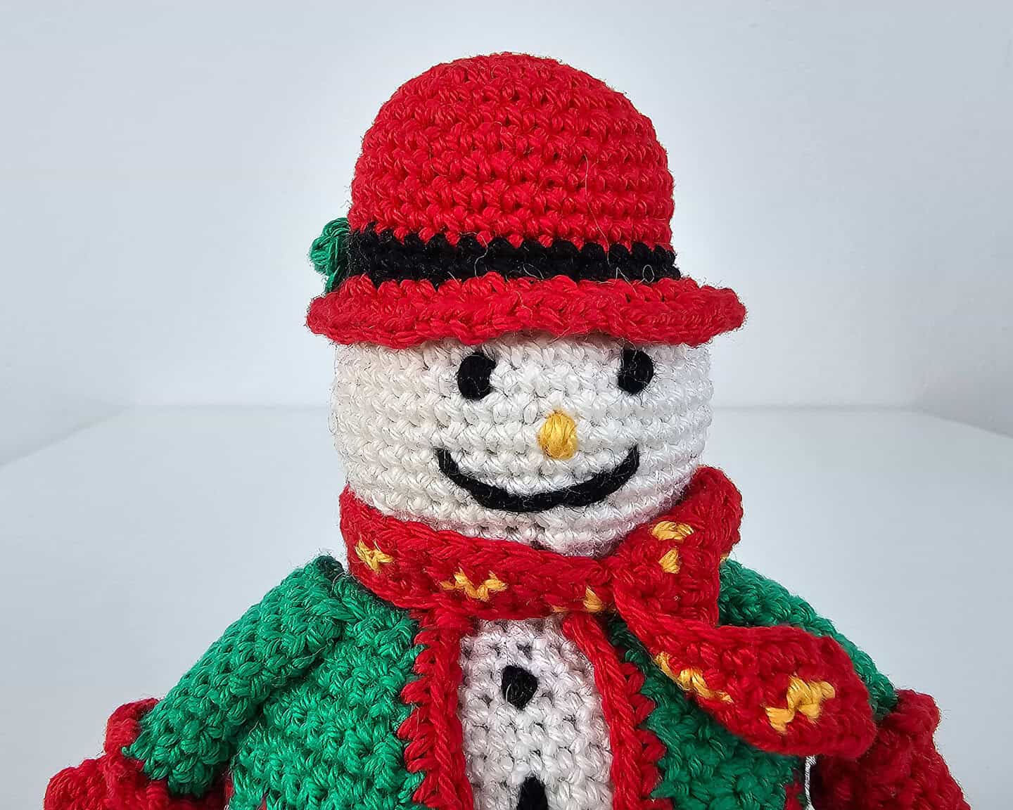 Fair-trade crochet snowman figure in holiday green and red outfit