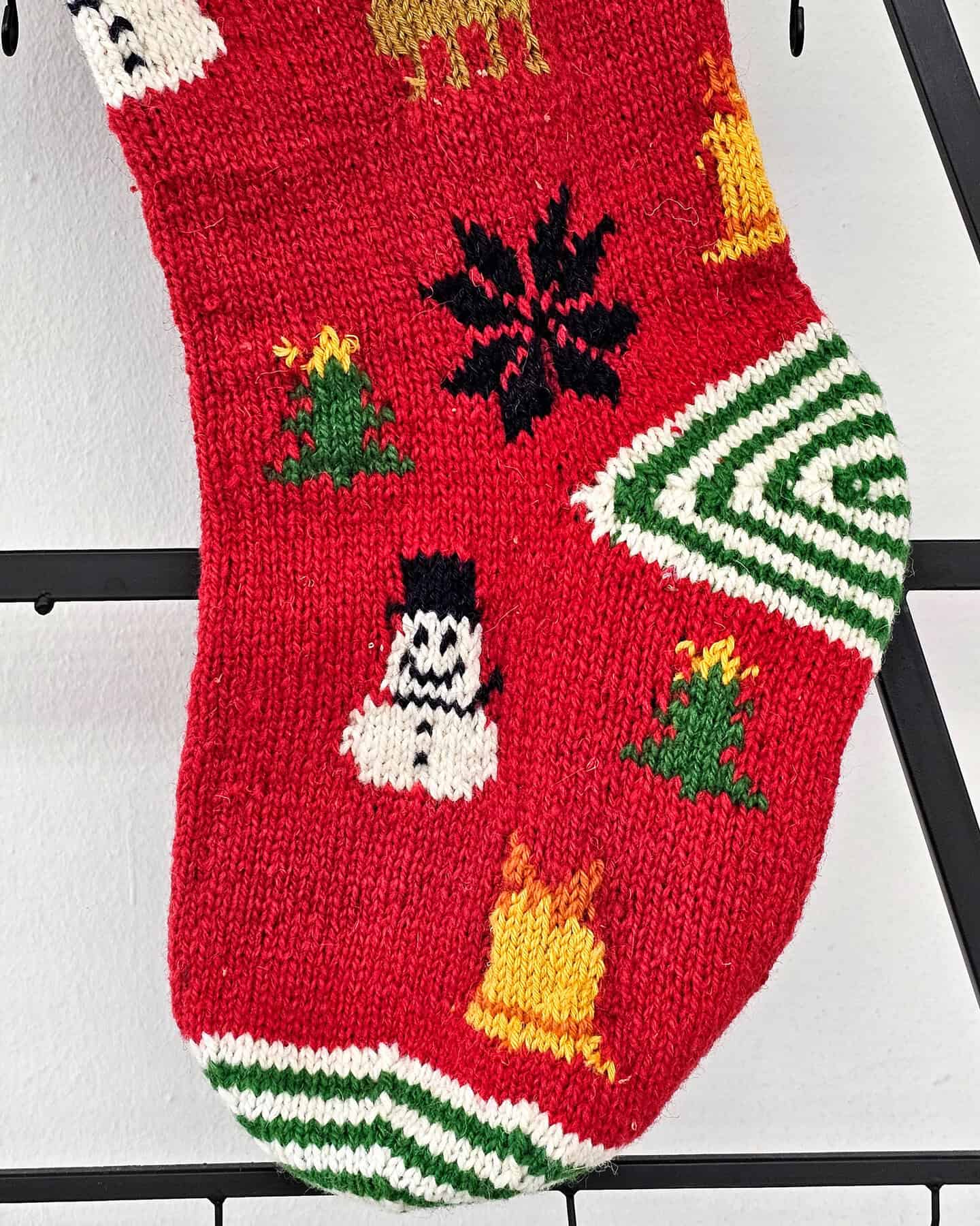 Hand-knitted Christmas stocking with cheerful snowmen design in red, white, and green colors