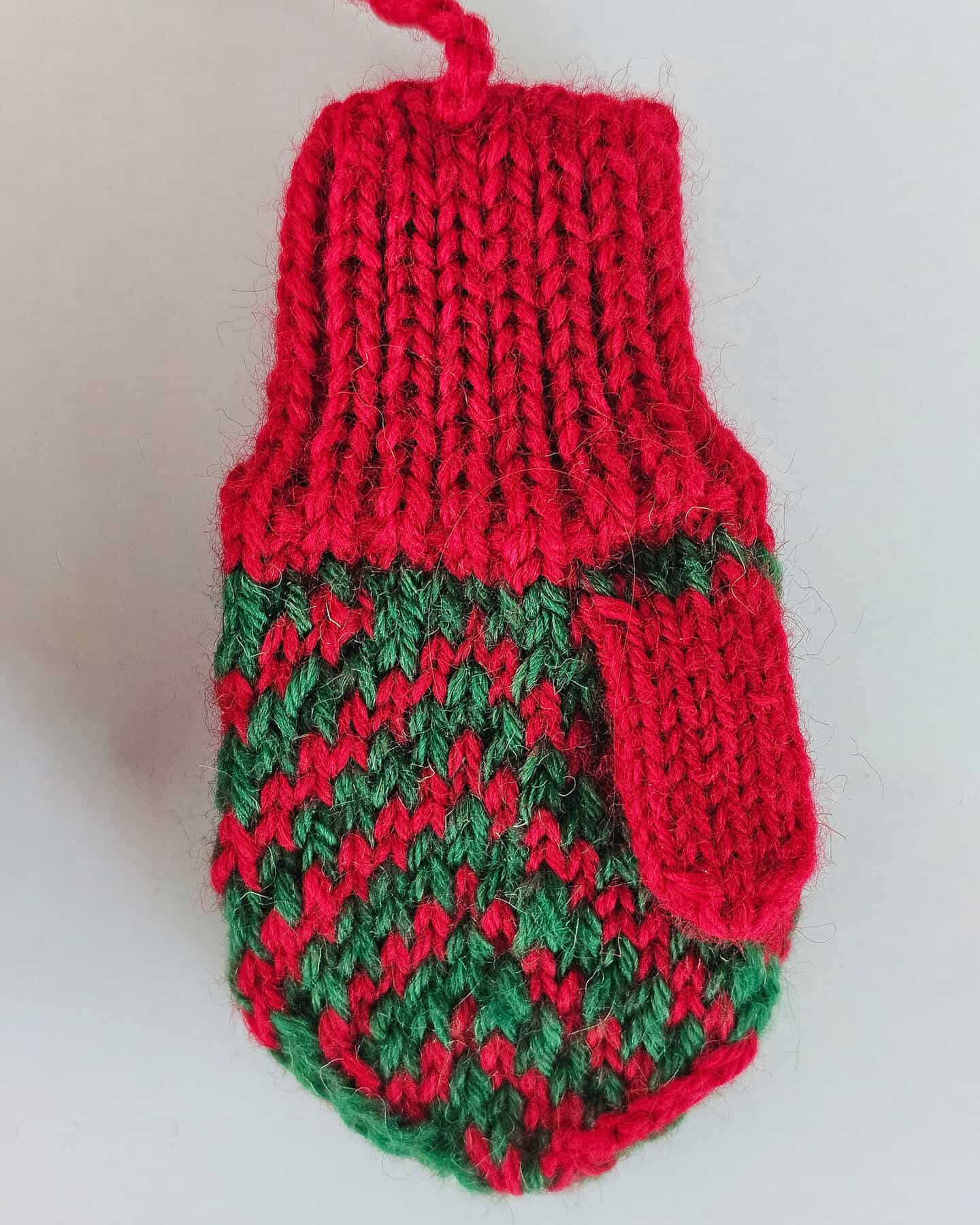 Mini knit Christmas mittens in red cuff and green patterned body, handmade by BH Crafts