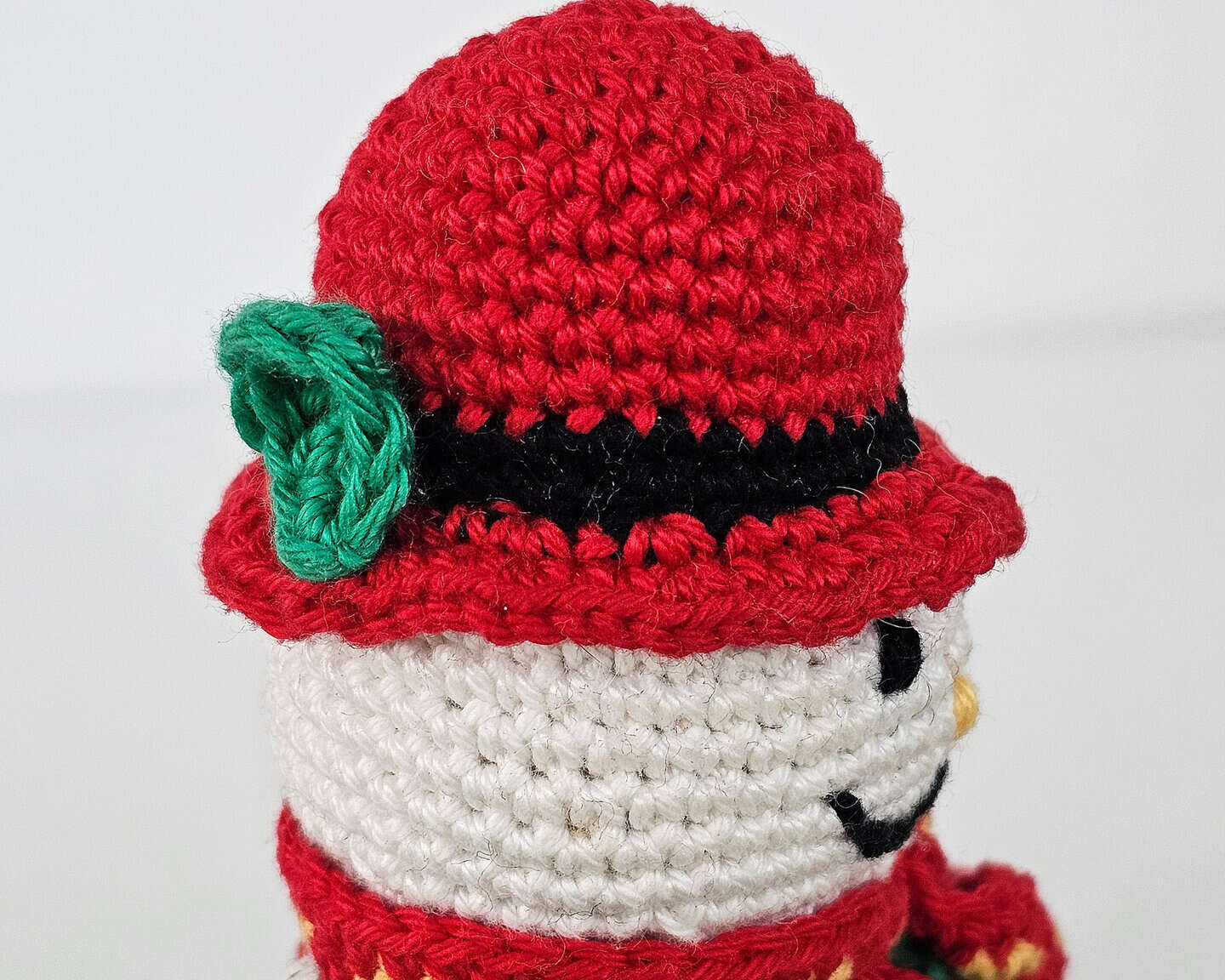 Handmade crochet snowman figure with red hat and green jacket