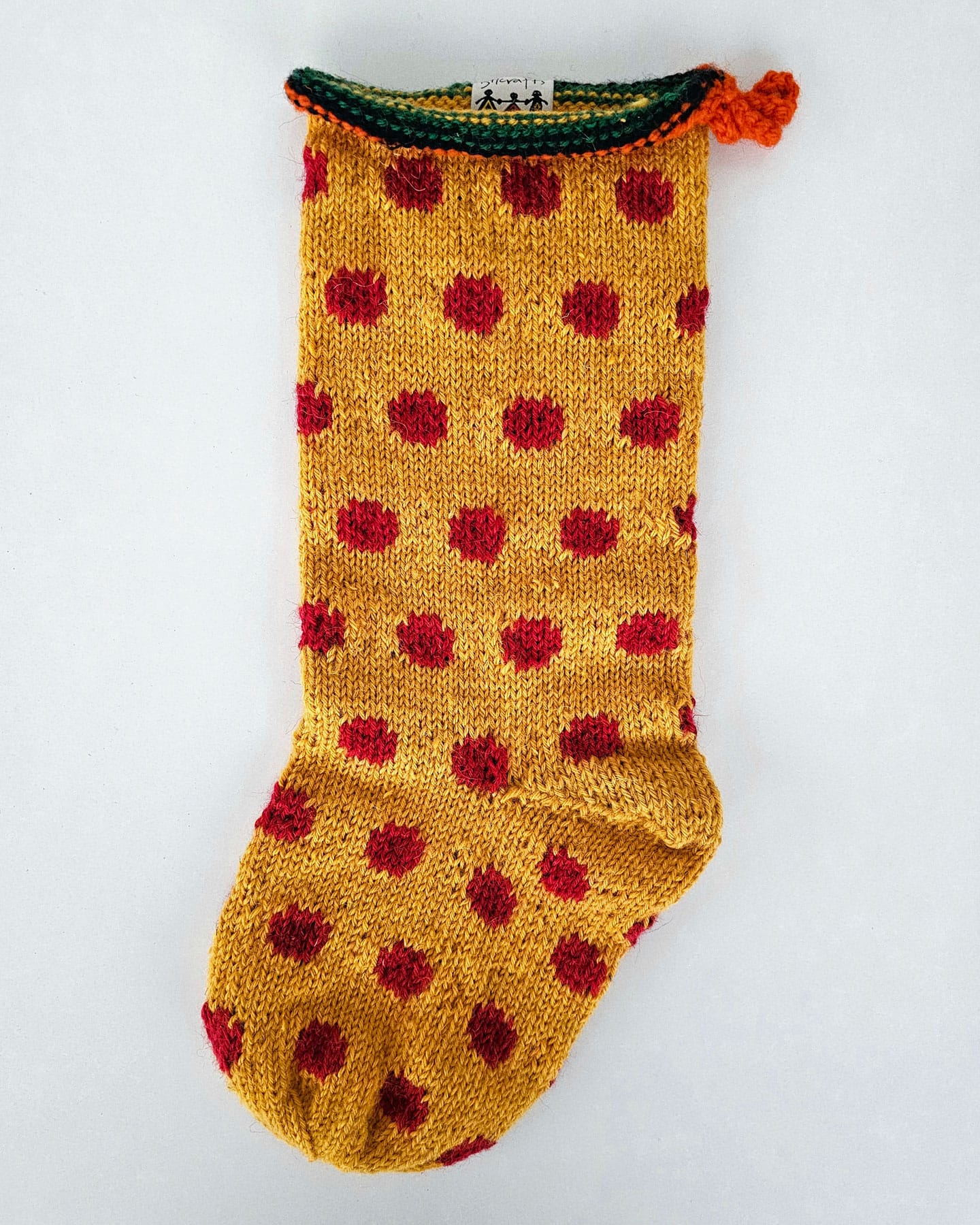 Hand-knit fair-trade Christmas tree stocking in mustard yellow with red polka dot pattern