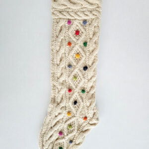 White hand-knit Christmas stockings with colorful dotted patterns and pom-poms