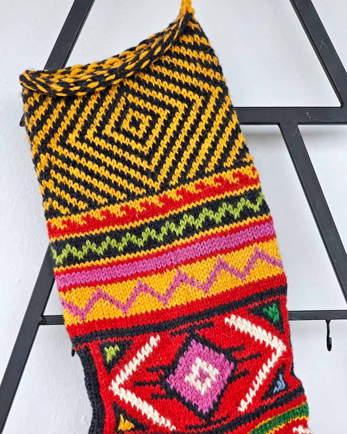 Handmade holiday stocking in red, green, yellow, and black colorwork design